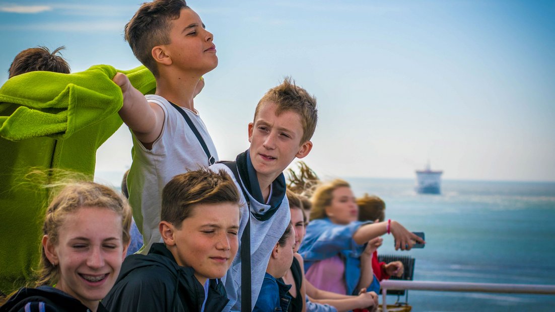 Young people on the deck of a ship enjoy the view.