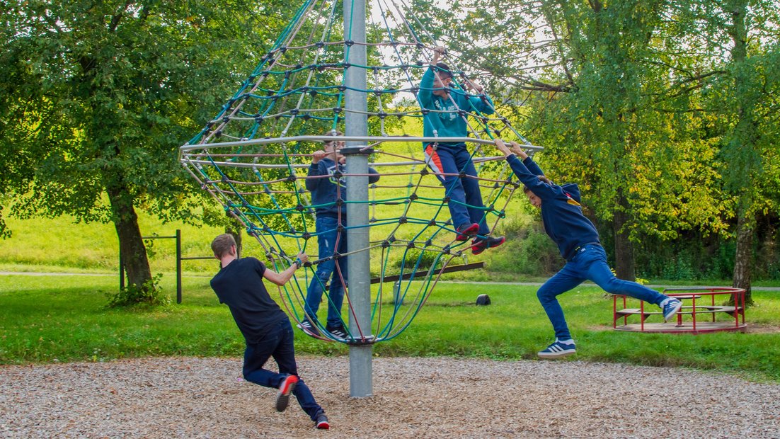 Young people have fun together on a climbing carousel.
