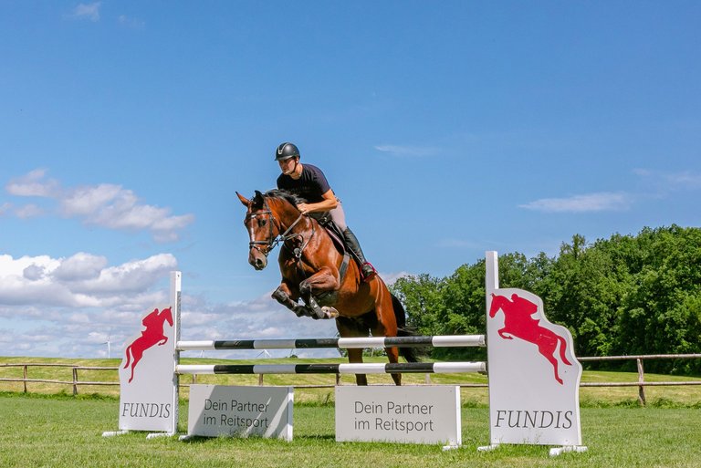 Martin Fundis on his horse overcoming a steep jump in the paddock