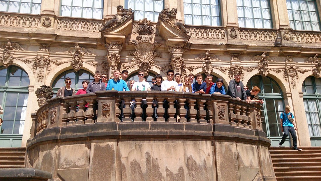 A group of students stands on a balcony of a historic building.